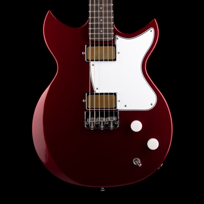Red electric guitar with a white pickguard on a black background
