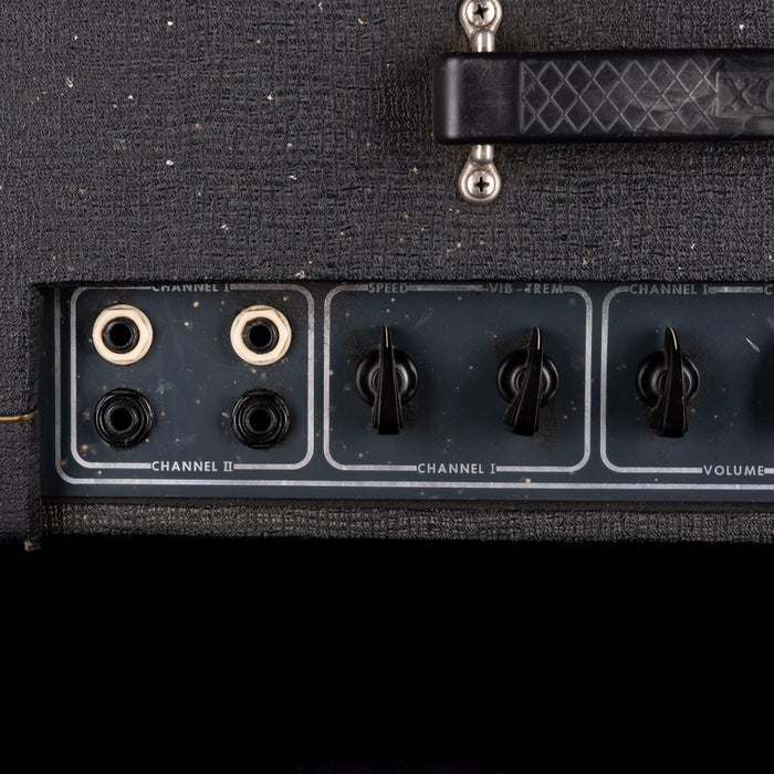 Close-up of a guitar amplifier with control knobs and jacks on a black background