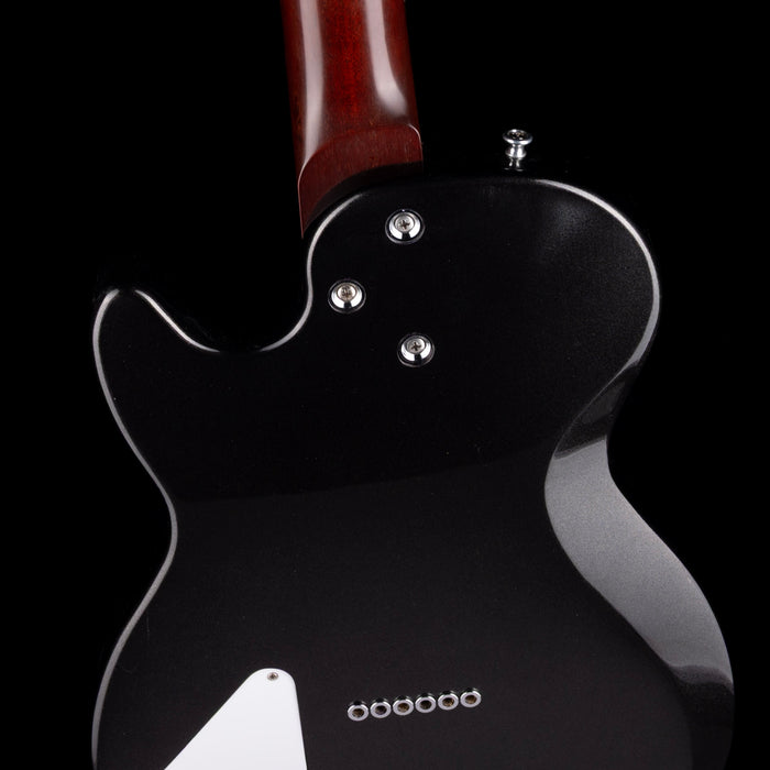 Close-up of a black electric guitar with a wooden neck on a black background