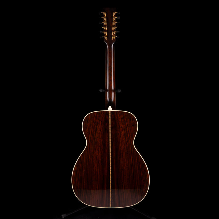 Wooden acoustic guitar on a stand with a black background