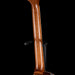 Close-up of a wooden guitar neck on a black background