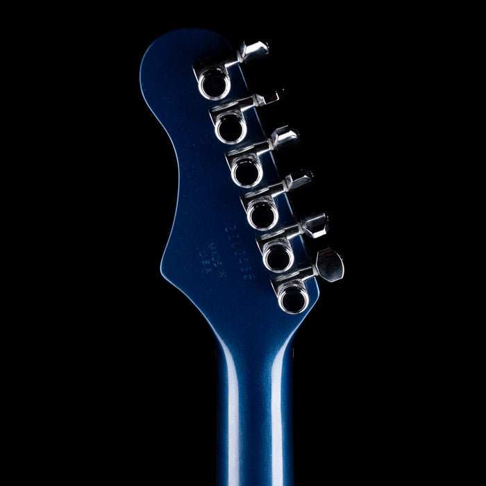 Close-up of a blue electric guitar's headstock with tuning pegs on a black background