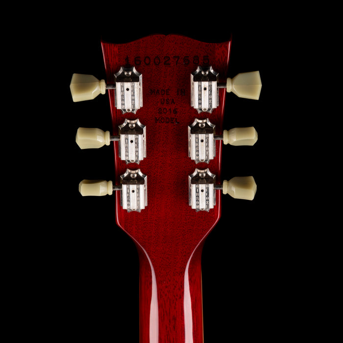 Close-up of a red guitar headstock with tuning pegs on a black background