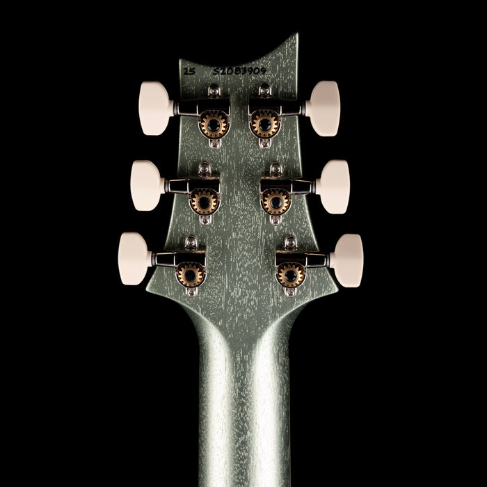 Close-up of a guitar headstock with six tuning pegs on a black background