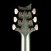 Close-up of a guitar headstock with six tuning pegs on a black background