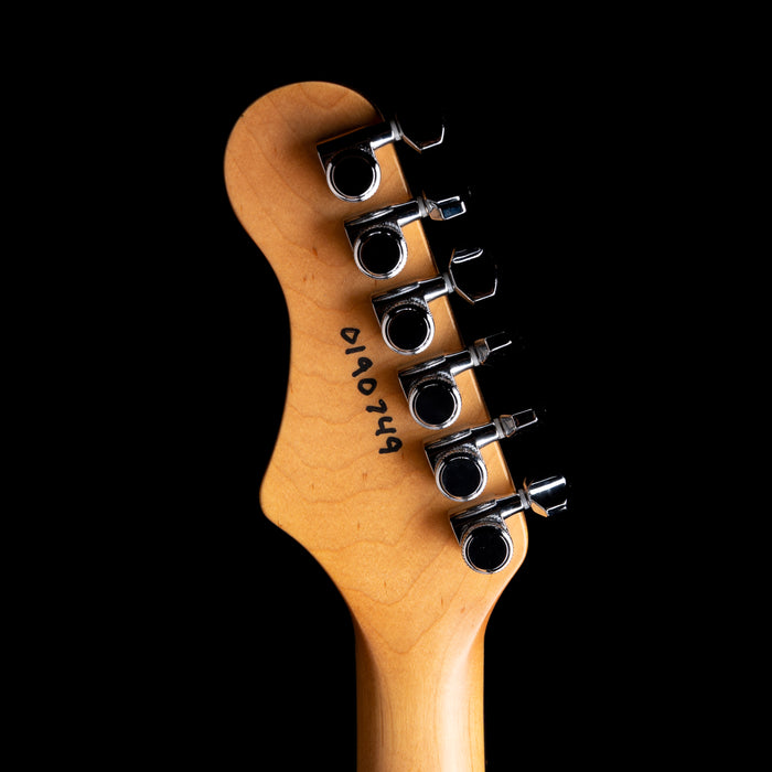 Close-up of a guitar headstock with tuning pegs on a black background