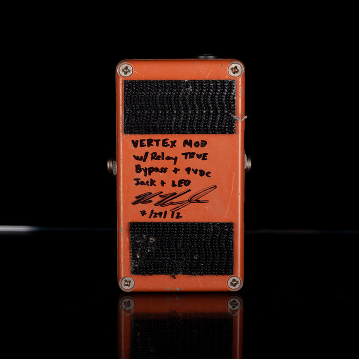Orange guitar effects pedal with black text on a black background