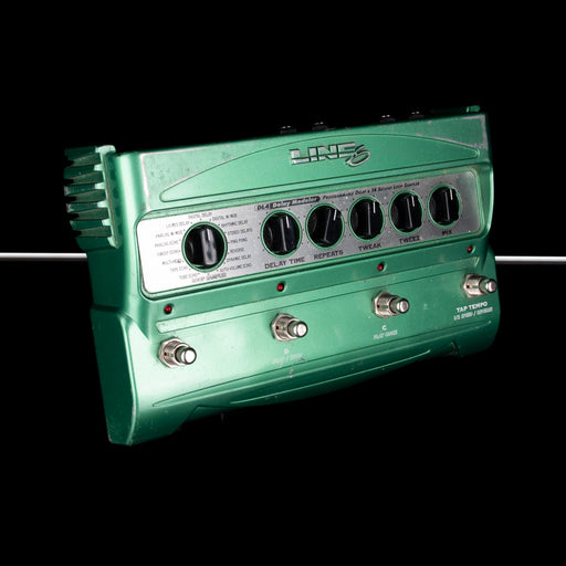 Green guitar effects pedal with control knobs on a black background