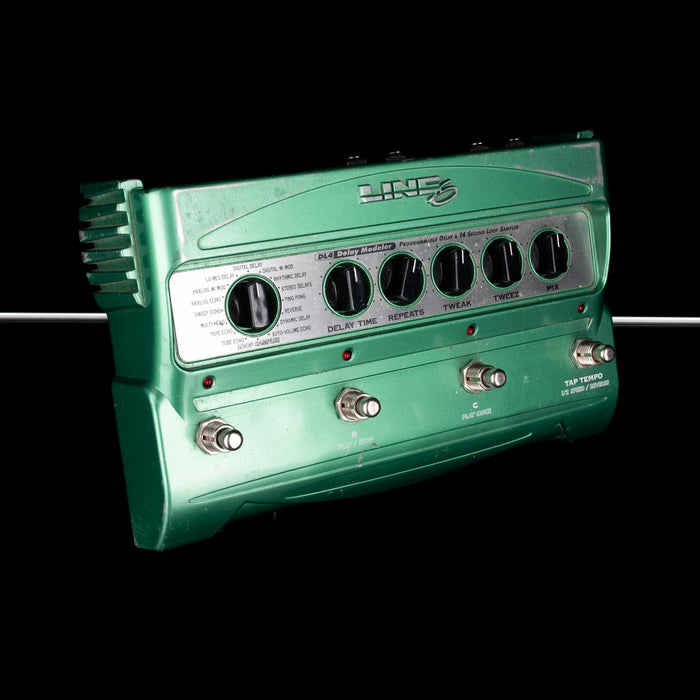 Green guitar effects pedal with control knobs on a black background
