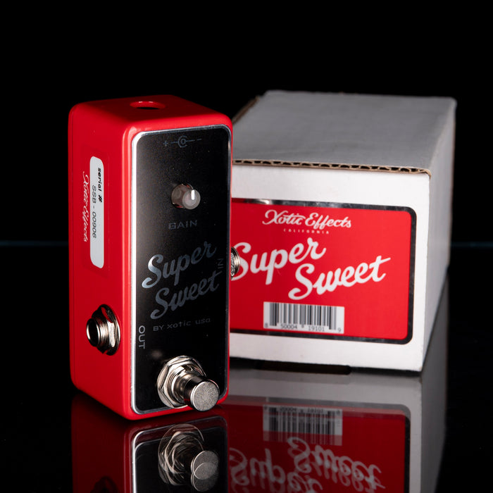 Red guitar effects pedal with 'Super Sweet' branding in front of a matching box on a reflective surface.