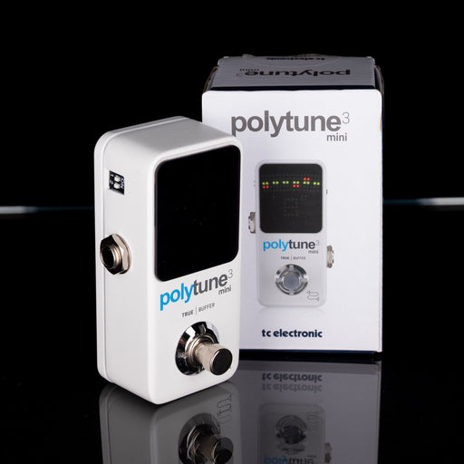 PolyTune mini guitar tuner with packaging on a reflective surface