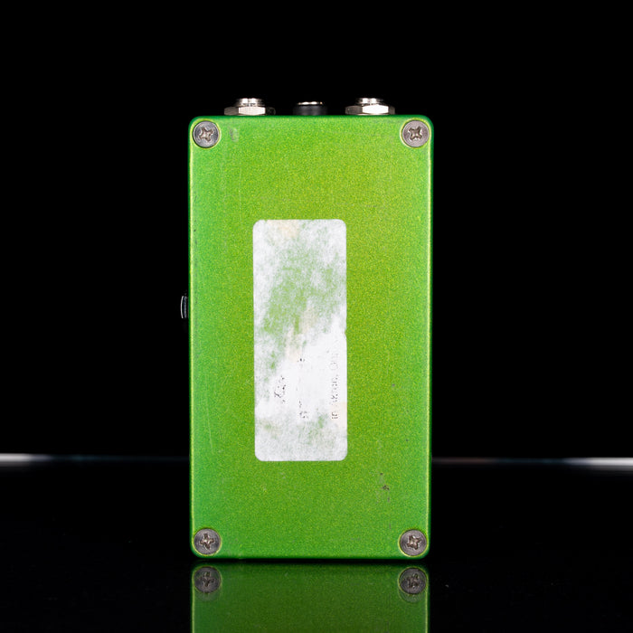 Green guitar effects pedal with a white label on a black background