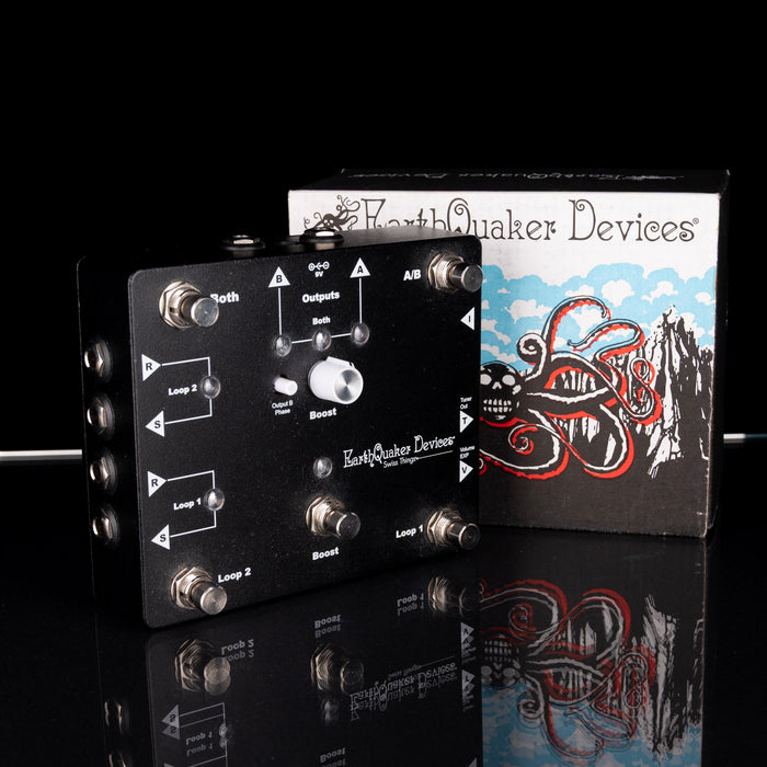 Guitar effects pedal with EarthQuaker Devices packaging on a reflective surface.