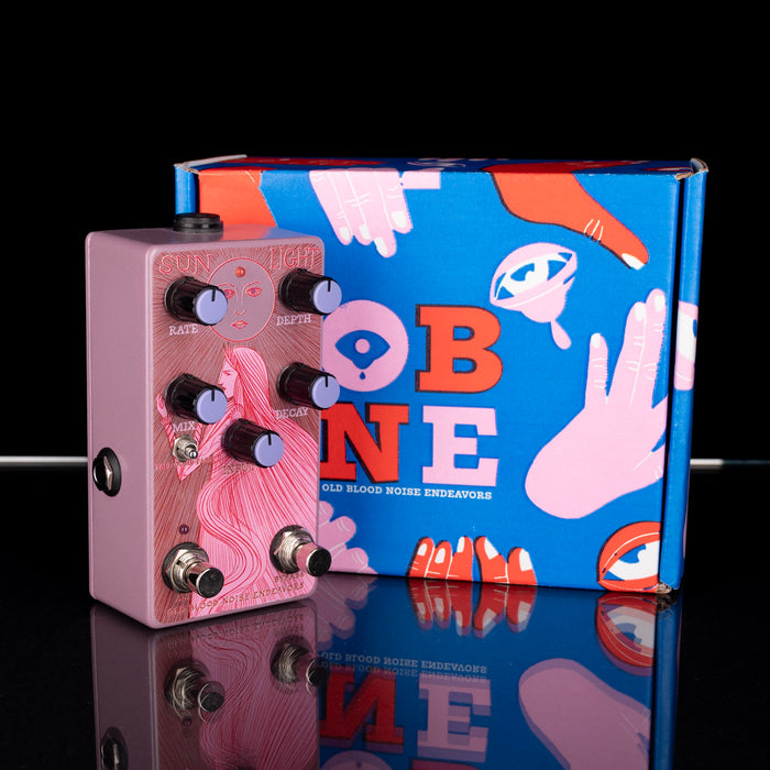 Pink guitar effects pedal with colorful OB1NE box on a reflective surface