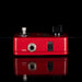 Red guitar effects pedal with input and output jacks on a black background