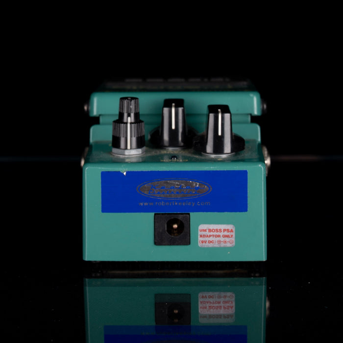 Green guitar effects pedal with three knobs on a black background