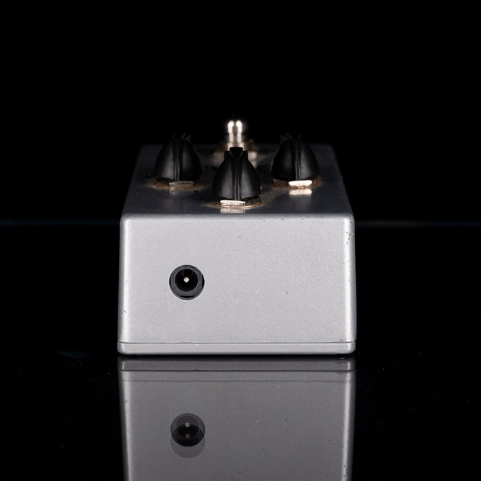 Metallic guitar effects pedal with four knobs on a black background