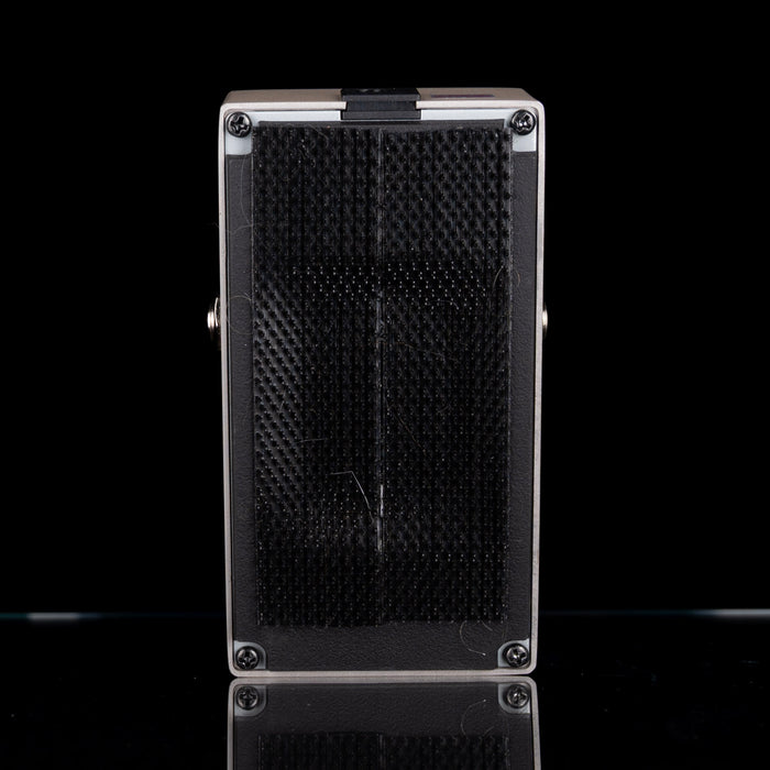 Black speaker grill on a reflective black surface with a white background