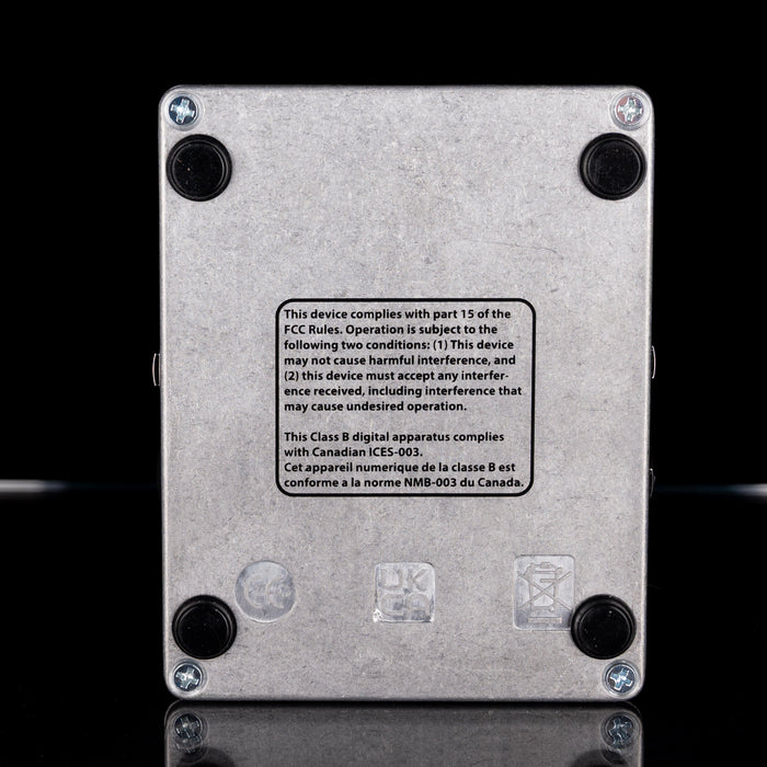 Back view of a metallic device with FCC compliance label on a black background