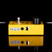 Yellow electronic pedal with control knobs on a black background
