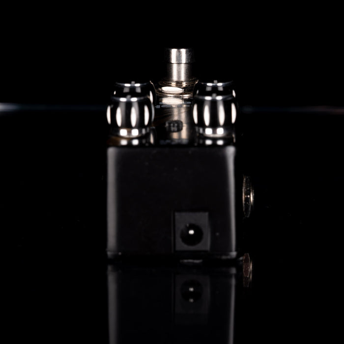 Metallic cylindrical objects on a reflective black surface with a dark background