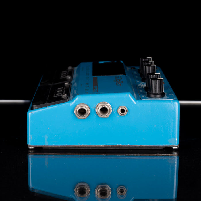 Blue guitar effects pedal with multiple jacks on a black background