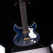 Blue electric guitar on a stand against a black background