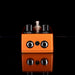 Orange guitar effects pedal with metallic knobs on a black background