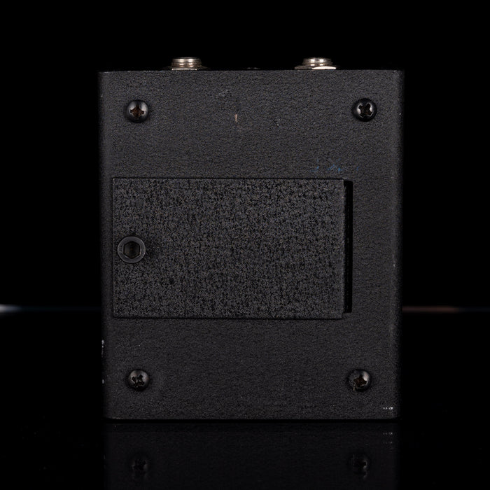 Black rectangular electronic device with textured surface and screws on a black background