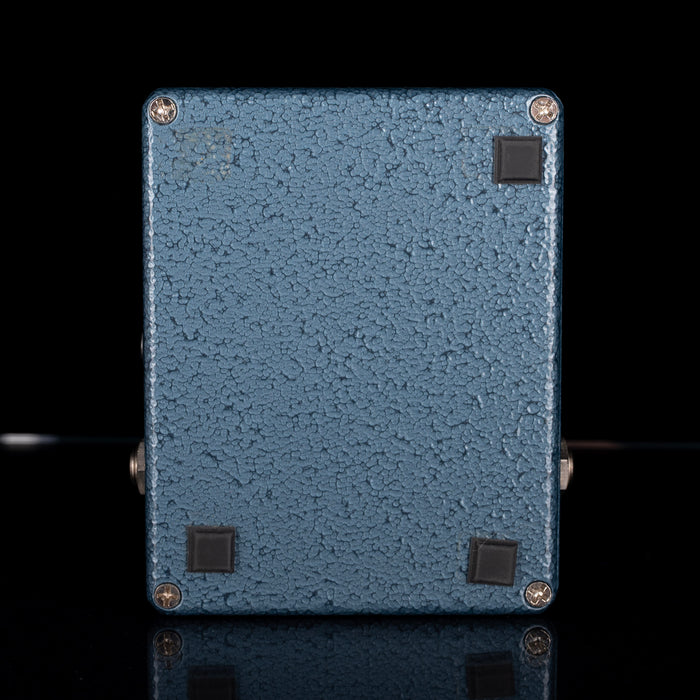 Blue textured rectangular object with screws on a black background