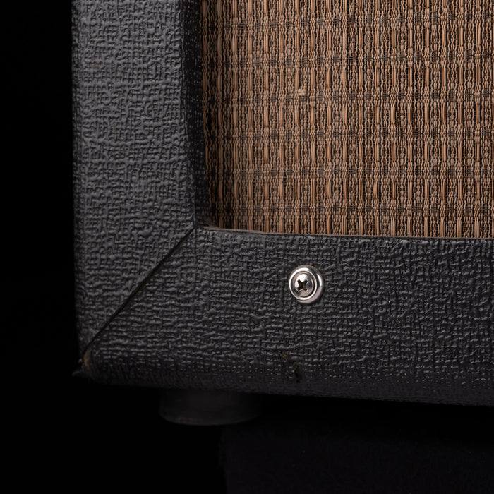 Close-up of a textured black speaker cabinet with a wooden panel.