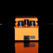 Orange guitar effects pedal with black knobs on a reflective surface.