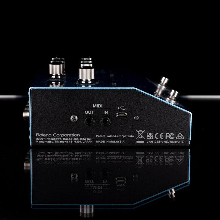 Back view of a Roland pedal with connectors and branding on a black background