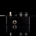 Black guitar effects pedal with metallic knobs on a reflective surface