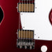 Close-up of a red electric guitar with white pickguard