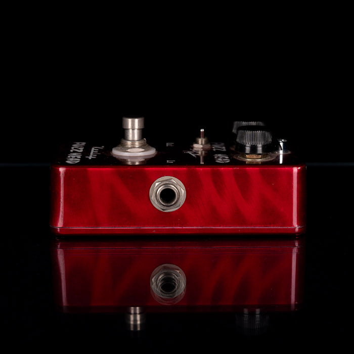 Red guitar effects pedal with metal components on a black background