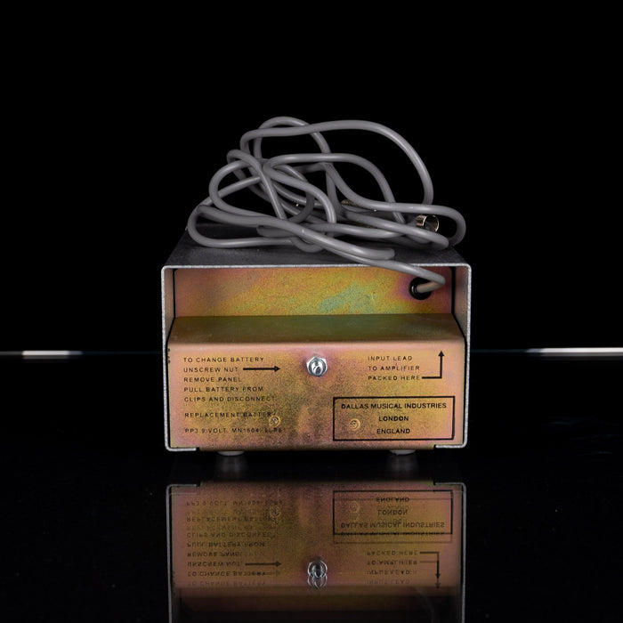 Vintage power supply unit with a coiled cable on a reflective surface.