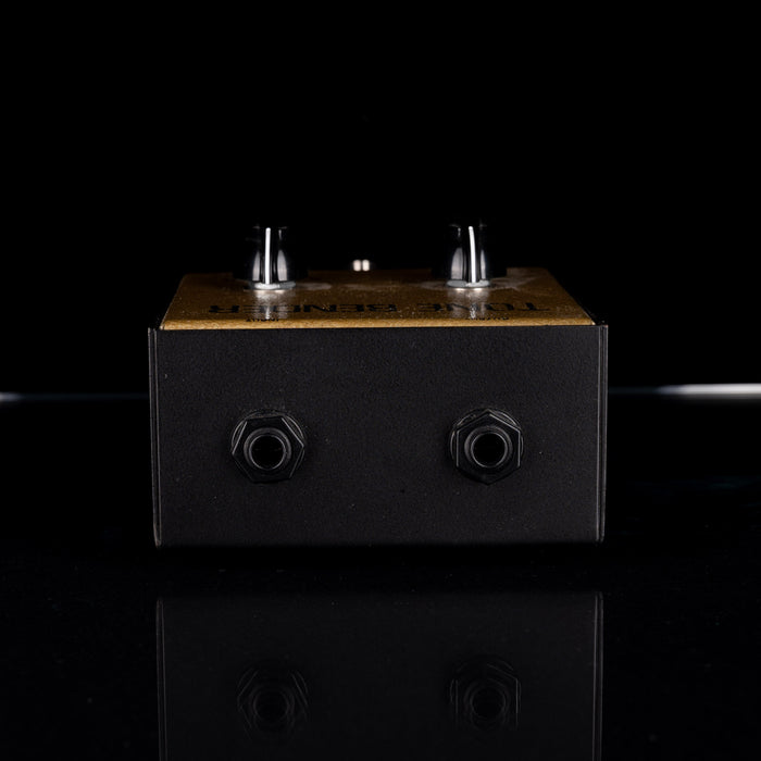 Black and wooden effect pedal on a reflective surface with a black background