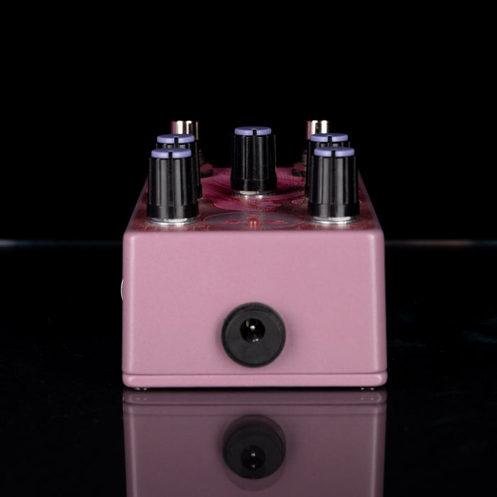 Pink guitar effects pedal with six knobs on a black background