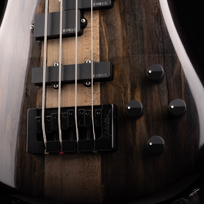 Close-up of a bass guitar with wooden finish and visible brand name.