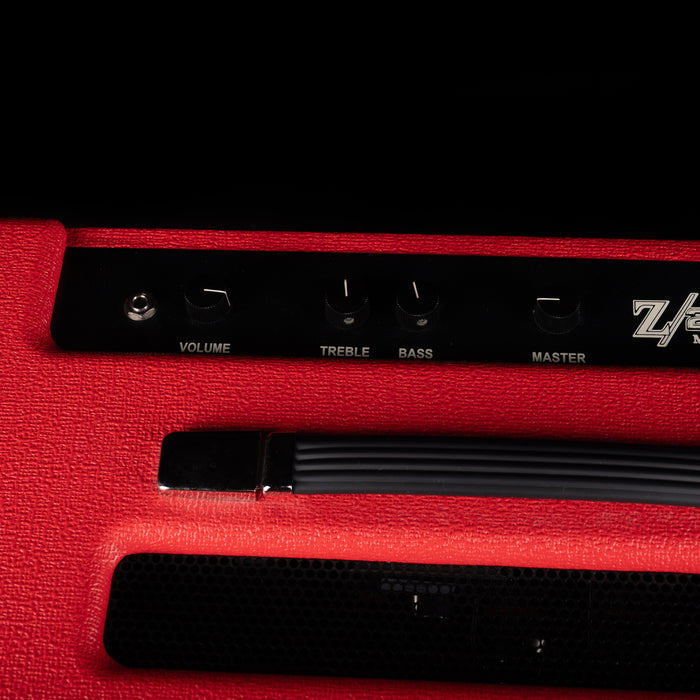 Close-up of a red guitar amplifier with control knobs on a black background