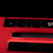 Close-up of a red guitar amplifier with control knobs on a black background