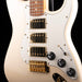 Close-up of a white electric guitar with gold hardware on a black background