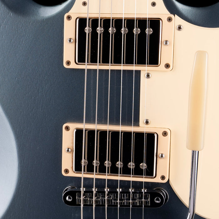 Close-up of a guitar with a blue body and white pickguard.