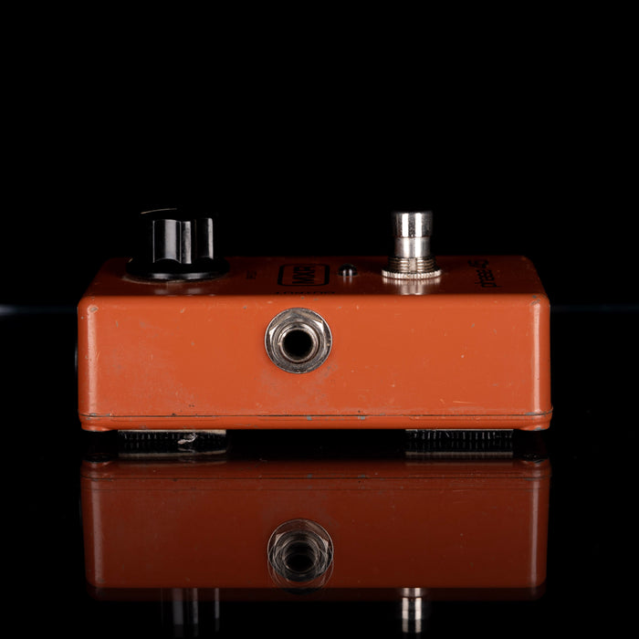 Brown guitar effects pedal with knobs on a black background