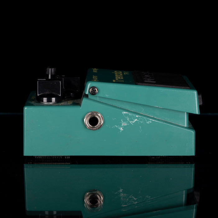 Teal guitar effects pedal on a black background