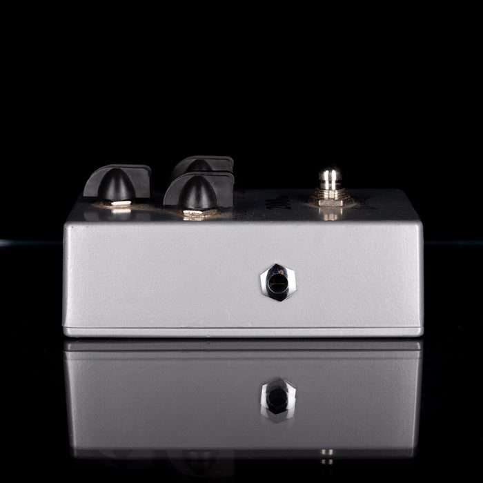 Guitar effects pedal with knobs and connectors on a black background