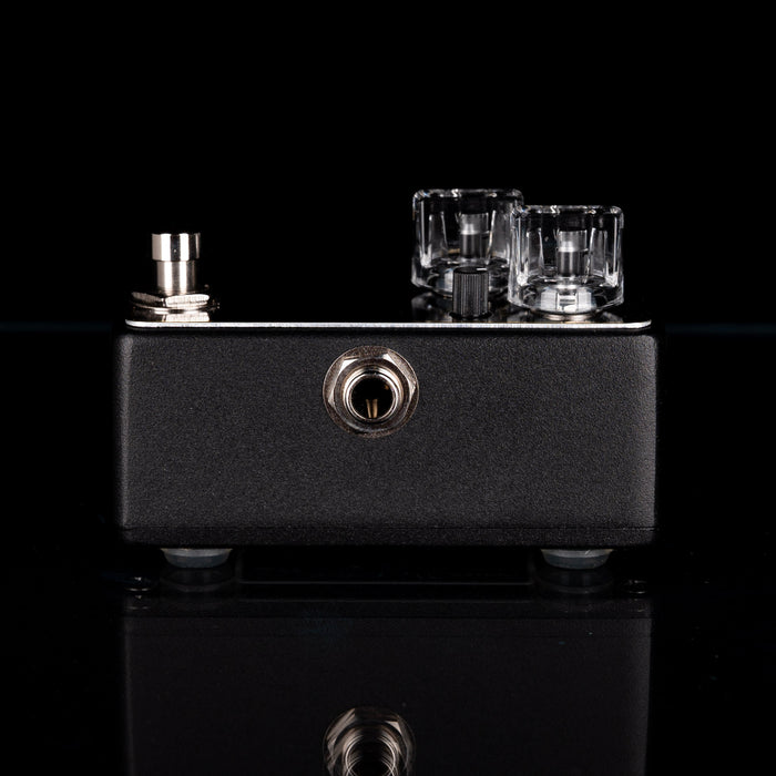 Black electronic pedal with glass components on a black background