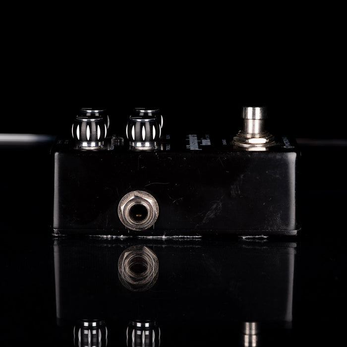 Black guitar effects pedal with metallic knobs on a black background