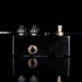 Black guitar effects pedal with metallic knobs on a black background
